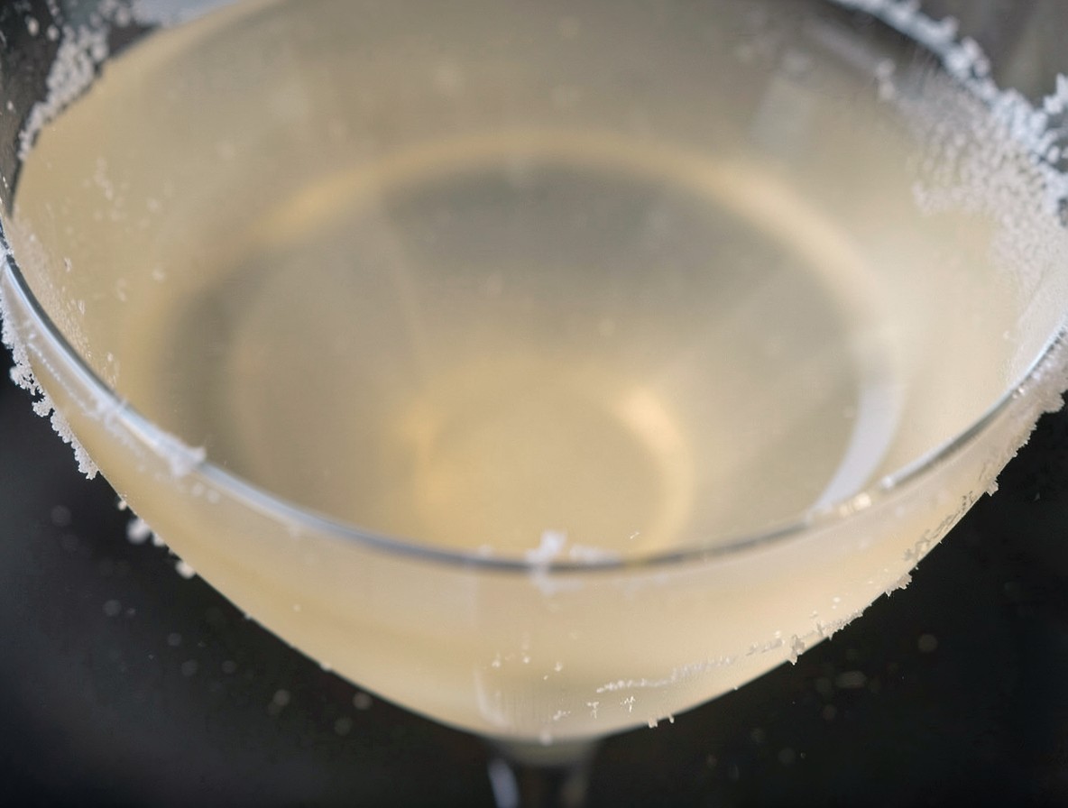 Macro shot of the clear, pristine surface of an amber Angel Face cocktail in a martini glass.