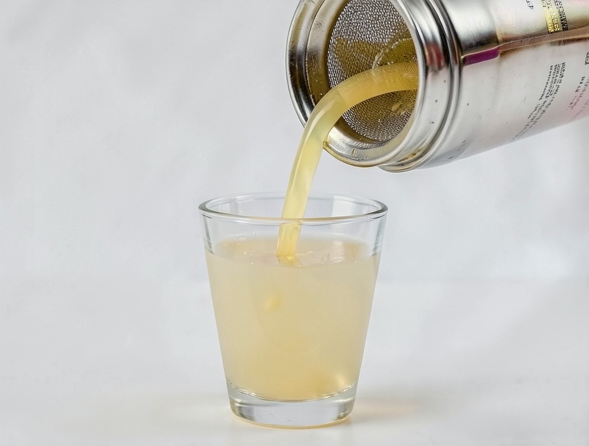 Straining pale golden chocolate cake shot into a chilled shot glass
