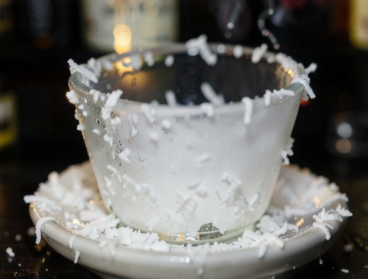 Close-up of a glass rim being coated with flaked coconut