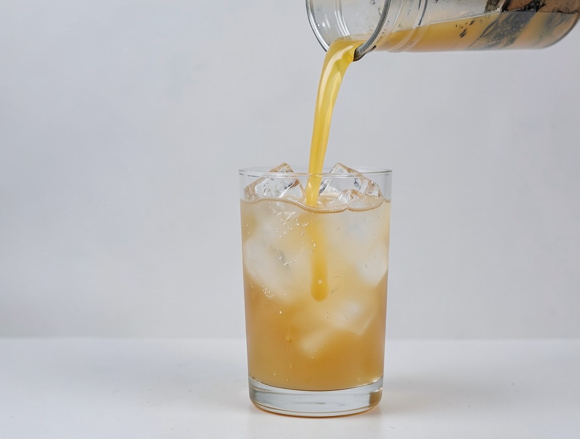 Pouring a Mai Tai from a cocktail shaker into a highball glass with ice