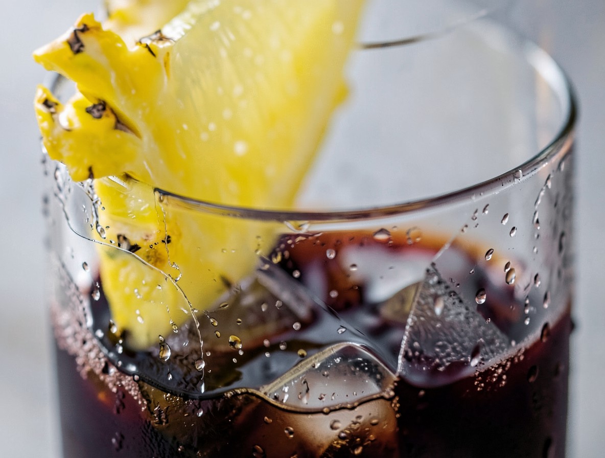 Pineapple wedge garnish on a Mai Tai with dark rum float and condensation
