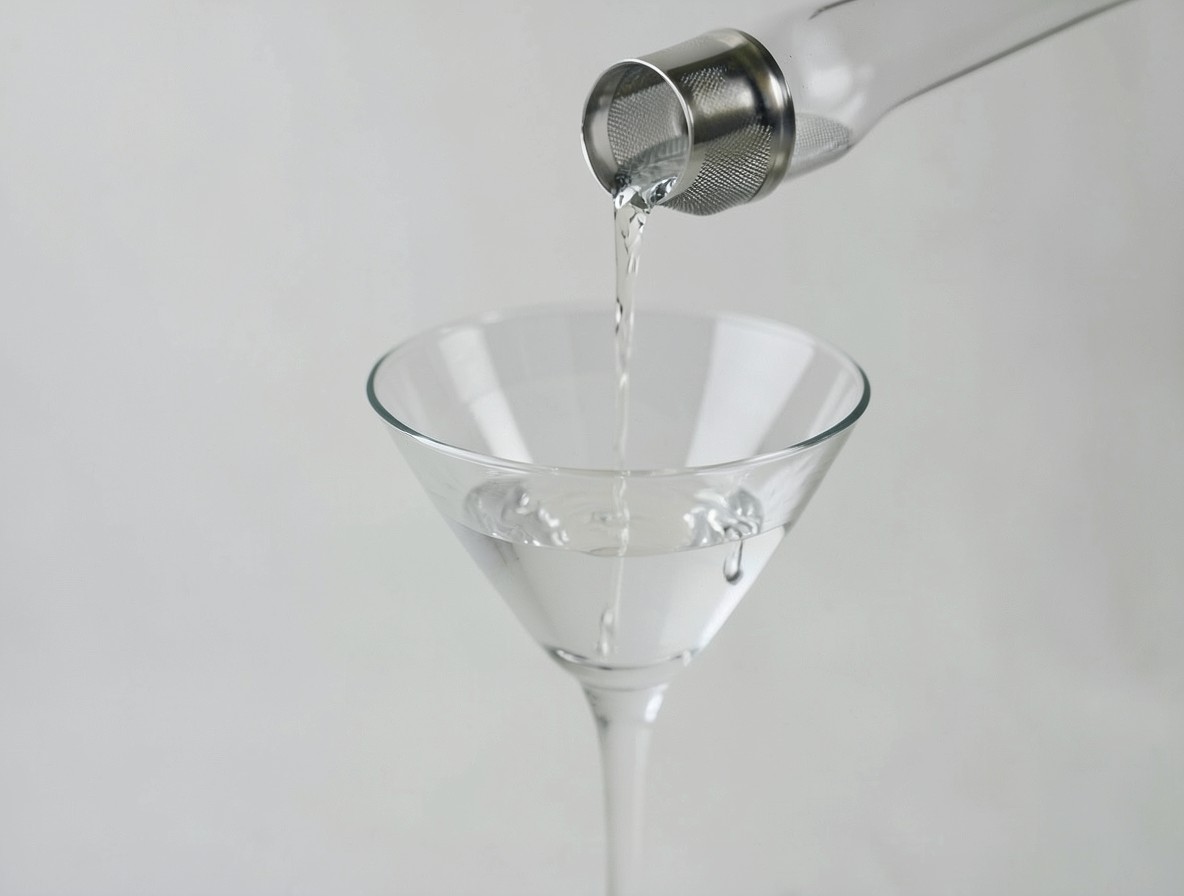 Straining a clear martini from a mixing glass into a chilled martini glass.