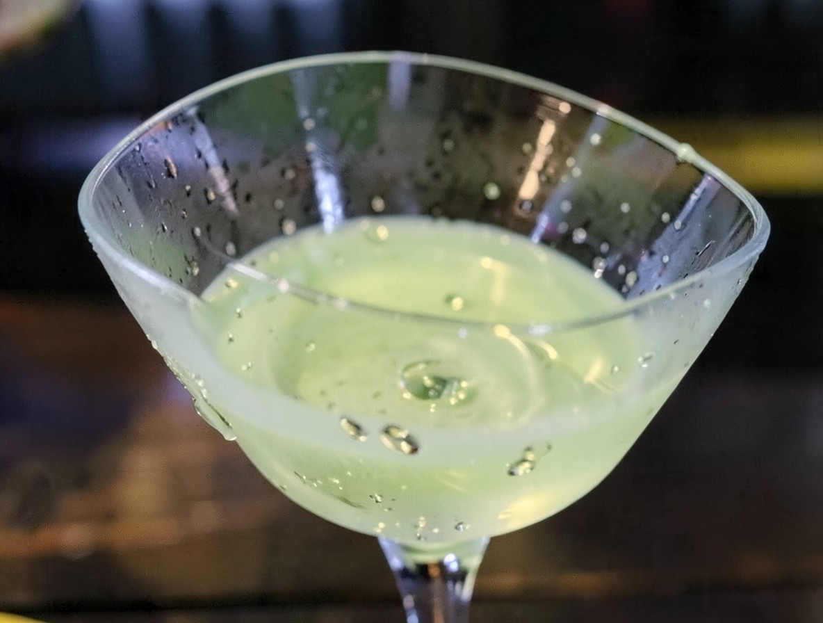 Close-up of absinthe rinsing the inside of a martini glass