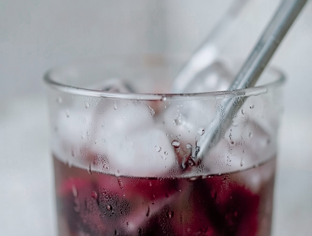 Negroni being stirred in a mixing glass with ice and a bar spoon, condensation on the glass
