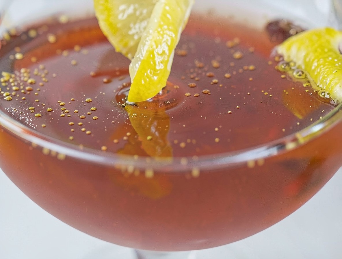 Expressing a lemon twist over a finished Paper Plane cocktail.