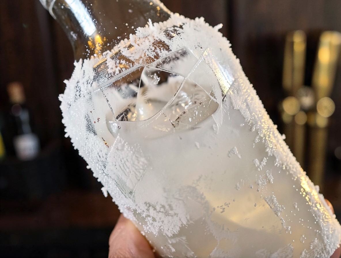 Frosted cocktail shaker with Snake Eyes drink ingredients and cracked ice