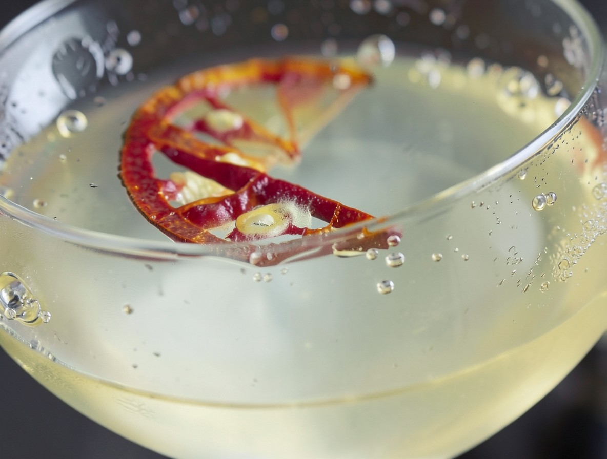 Macro shot of the Spicy Fifty cocktail, clear golden liquid with chilli and condensation.