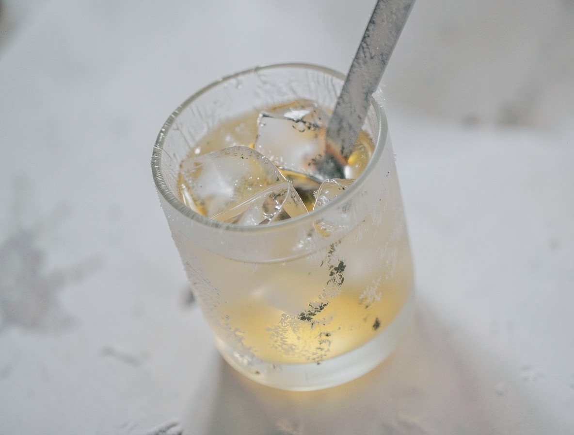 Mixing glass with ice and a clear Stinger cocktail being stirred.