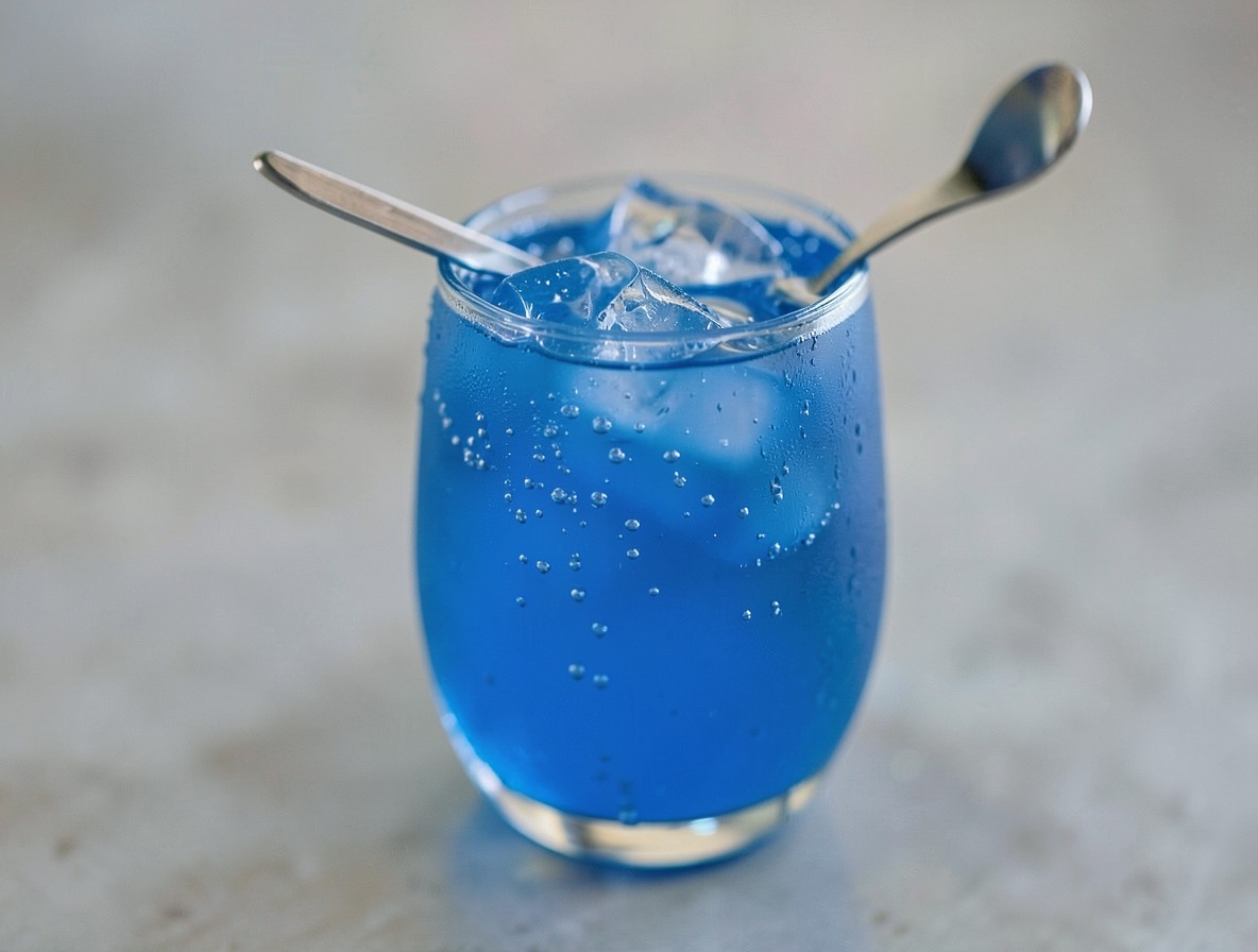 Stirred blue Venom cocktail in highball glass with bar spoon